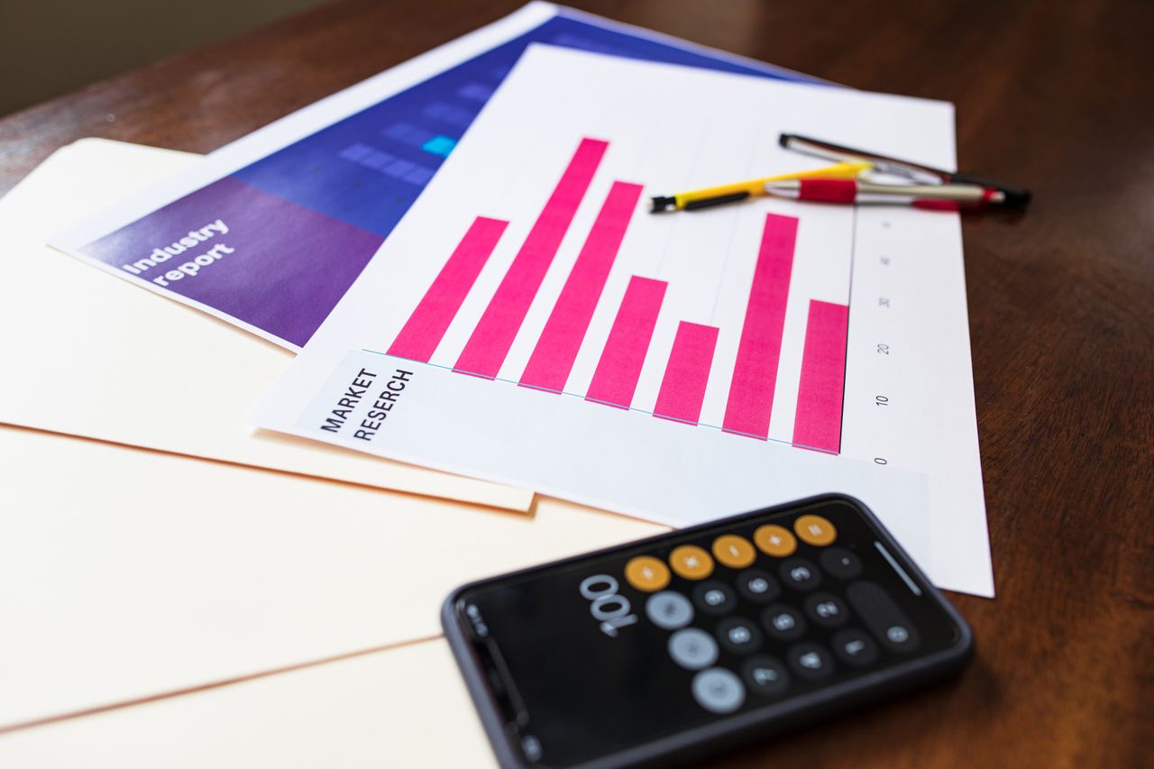 Illustration d’un graphique d’étude de marché et d’une calculatrice sur un bureau en bois pour l’analyse business.