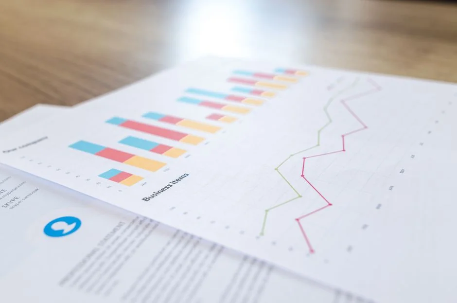Un espace de travail contemporain où des mains analysent des données marketing sur un ordinateur portable et des documents papier.